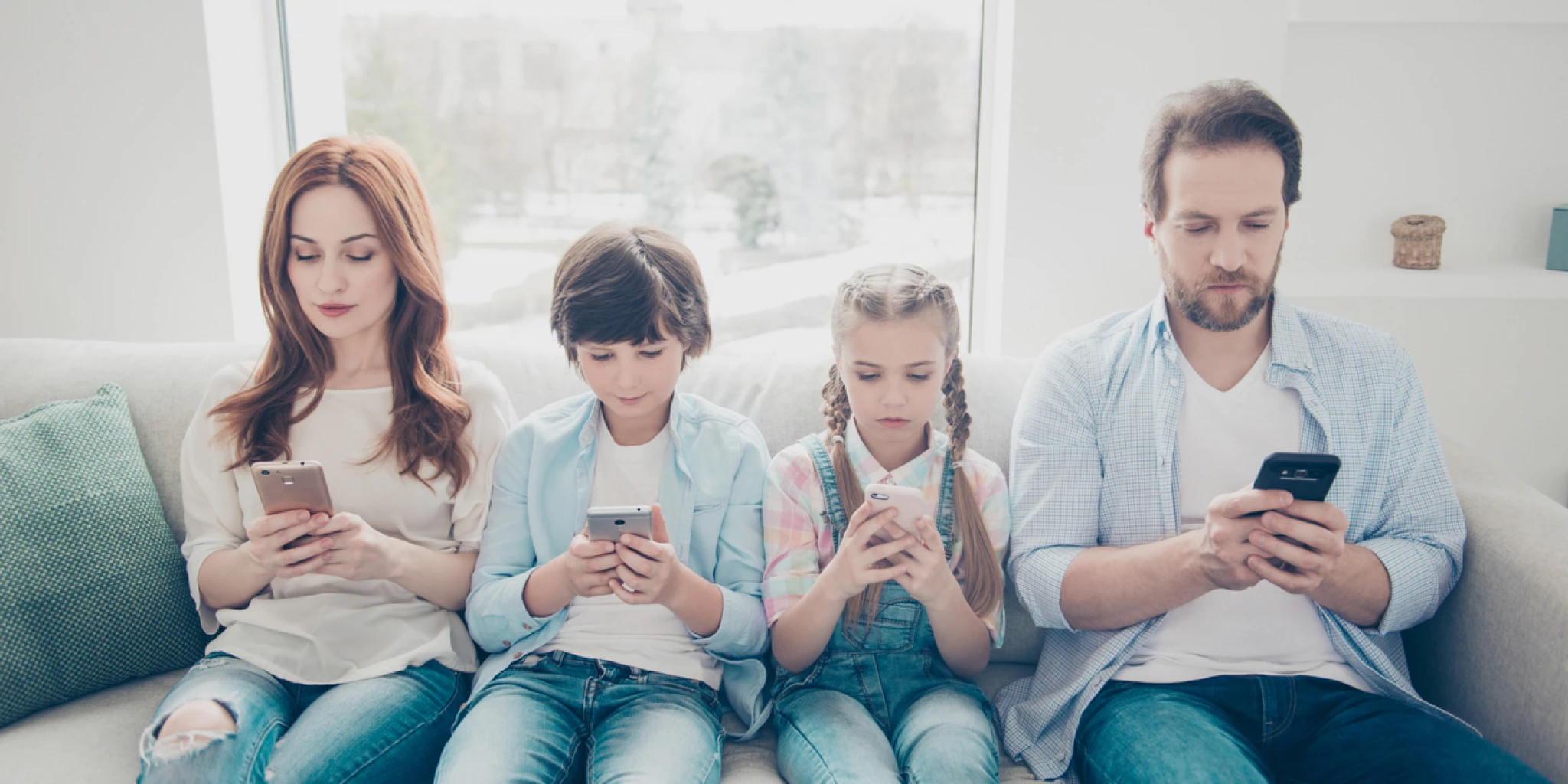 Portrait of family with two kids holding smart phones having electronic devices in hands texting sms using wi-fi 3G internet checking email searching contact. Apps concept