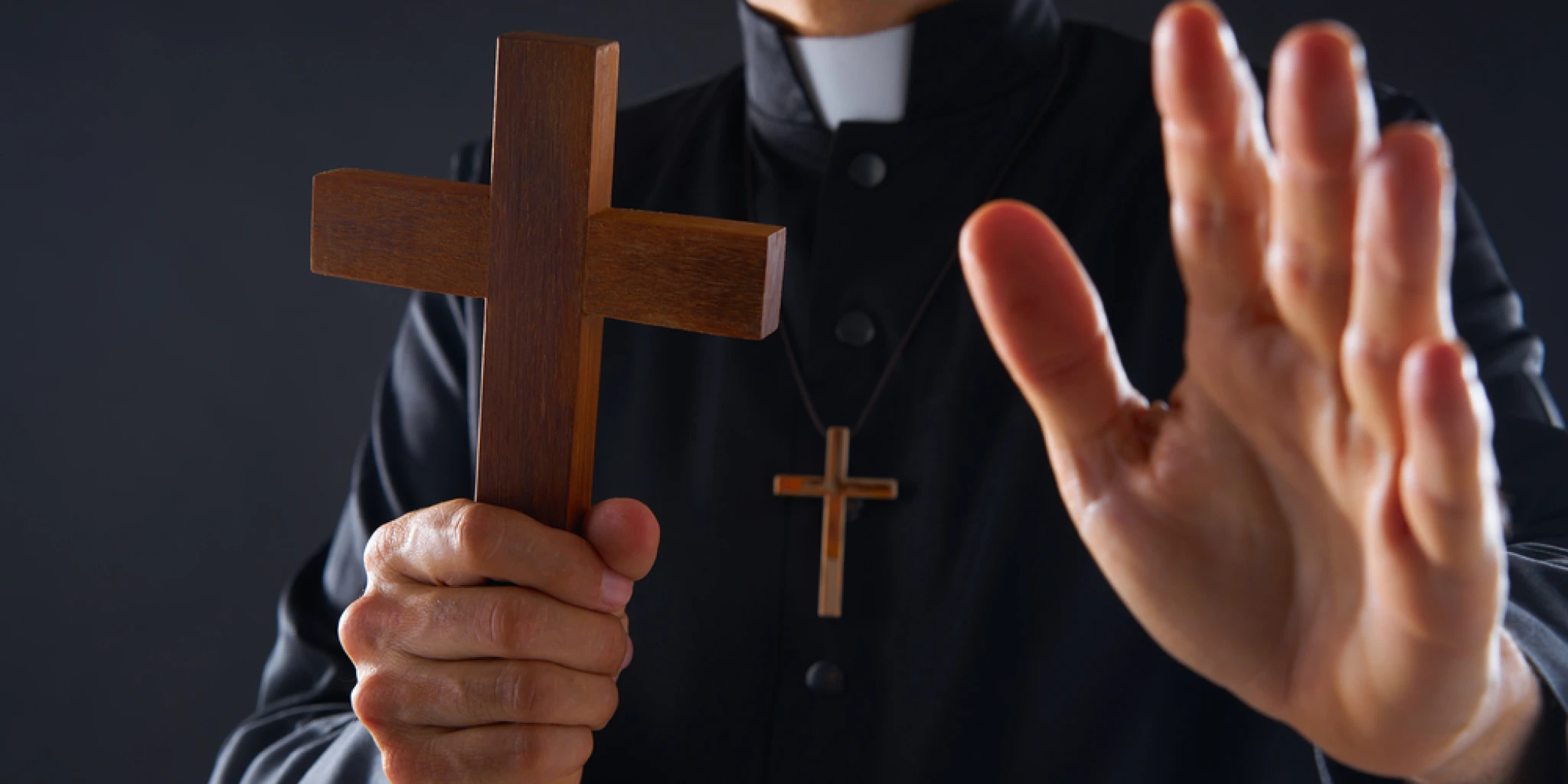Priest holding cross of wood praying